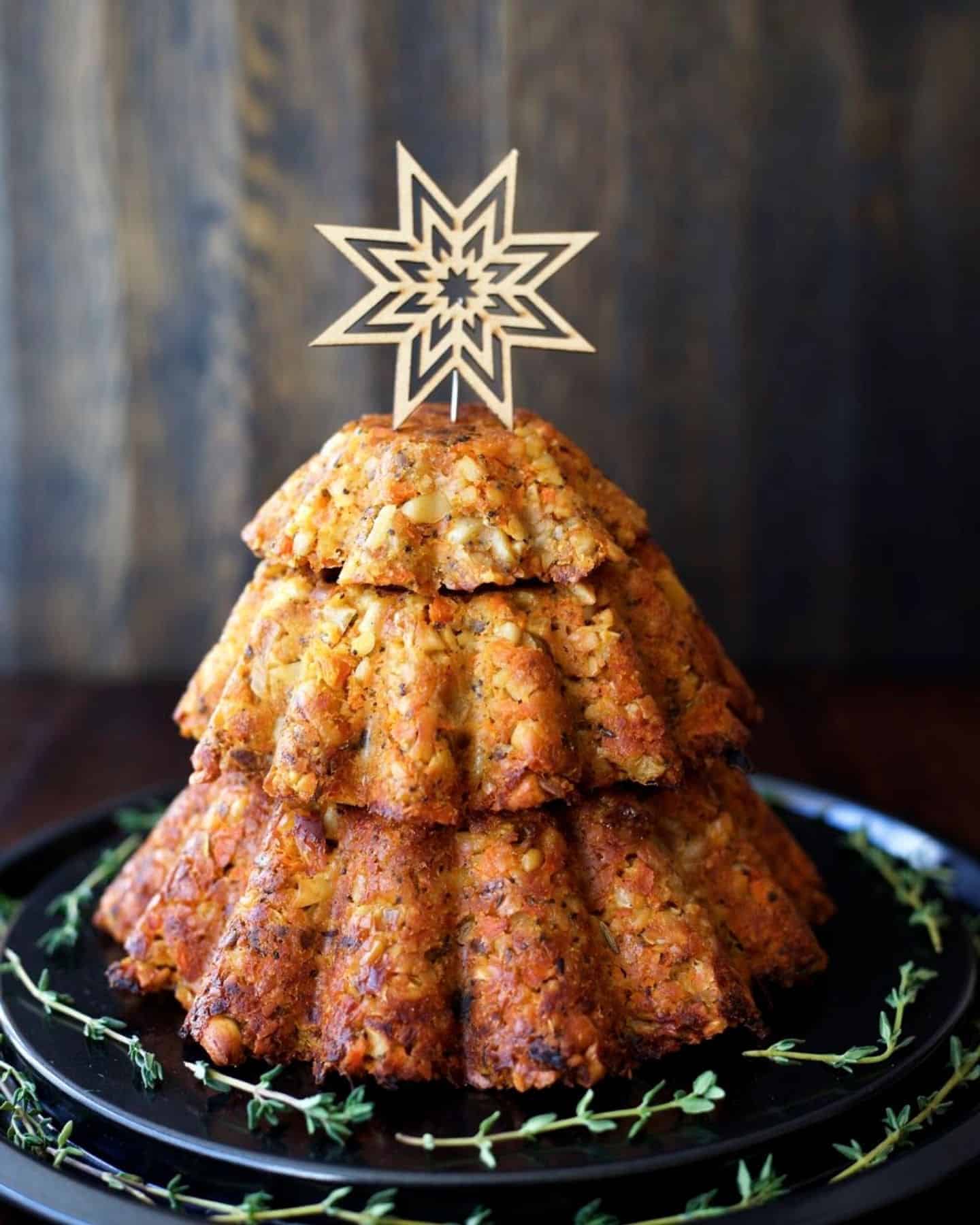 Nut roast in the shape of a Christmas tree topped with a star and fresh thyme around the bottom
