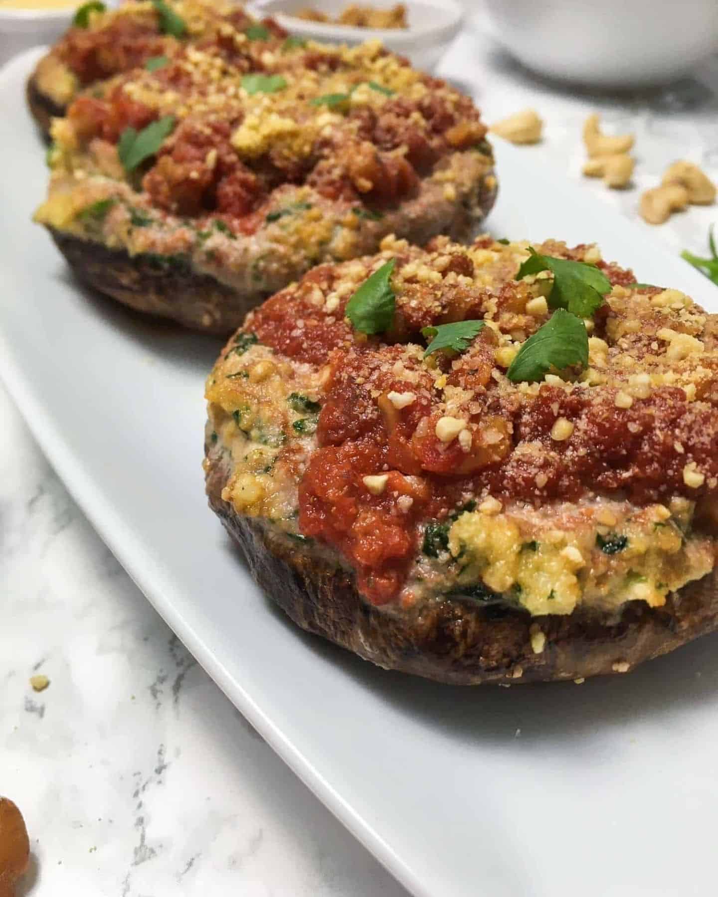 2 lasagne stuffed portobello mushrooms on a white serving plate