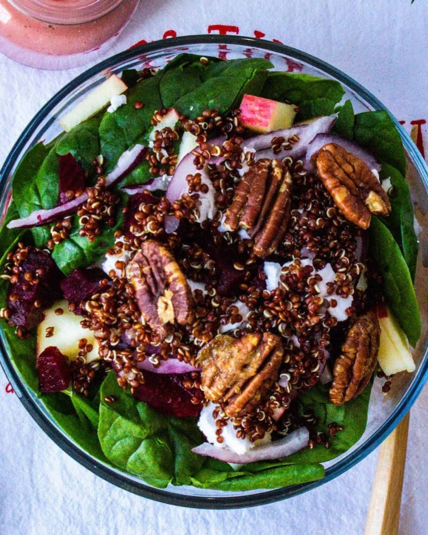 Festive holiday salad piled high on a plate with walnuts on top and spinach leaves visible