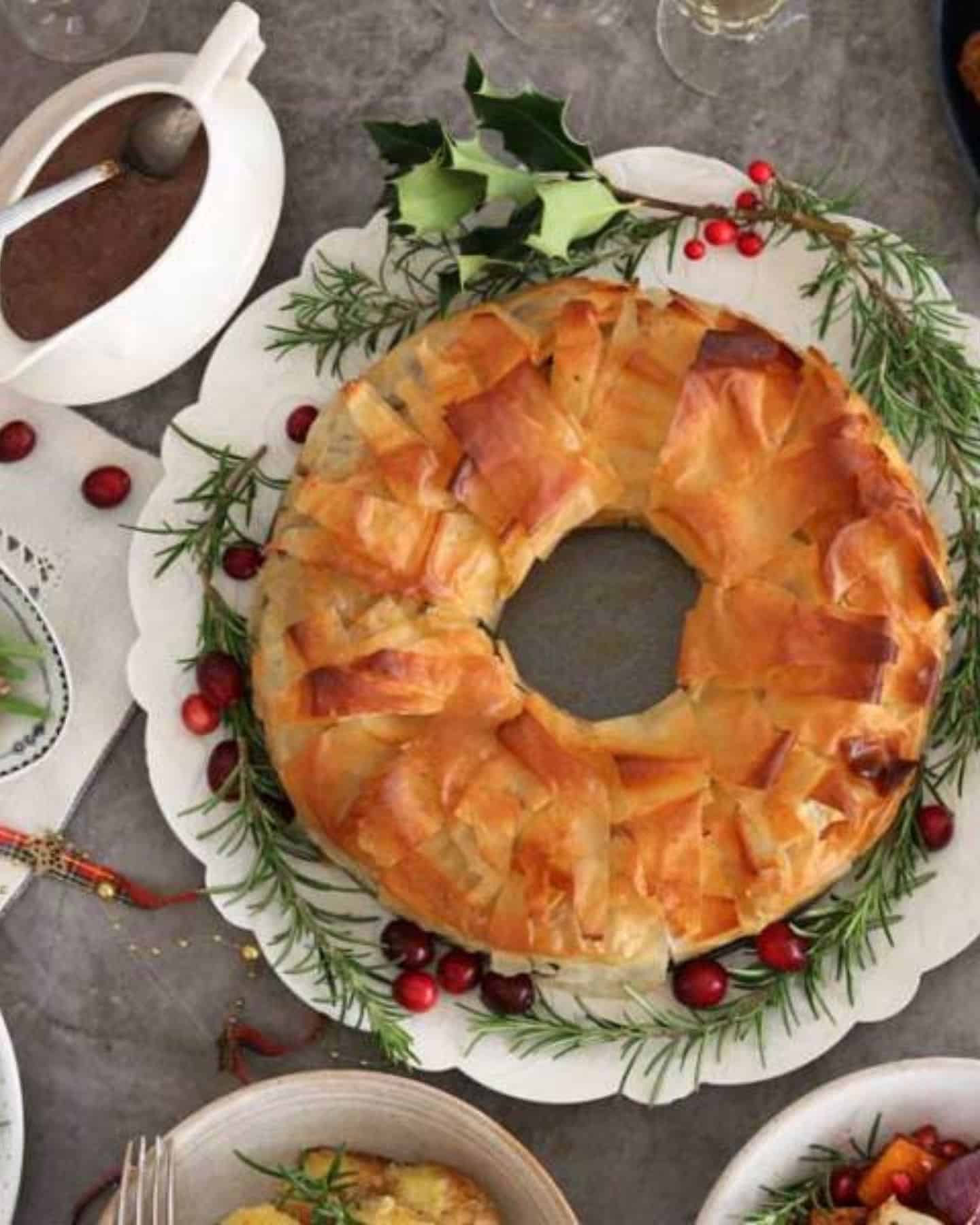 Vegan Christmas Filo Wreath served with gravy and holly is surrounding it