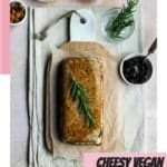 A Pinterest image titled Cheesy Vegan Cashew Nut Roast. The photo in the centre is a top-down shot of a golden brown nut roast with a sprig of thyme laying on top.
