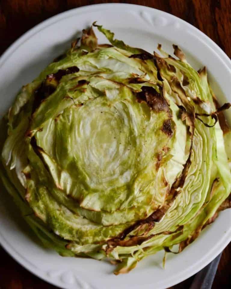 Slice of cabbage steaks on a white plate with crispy edges