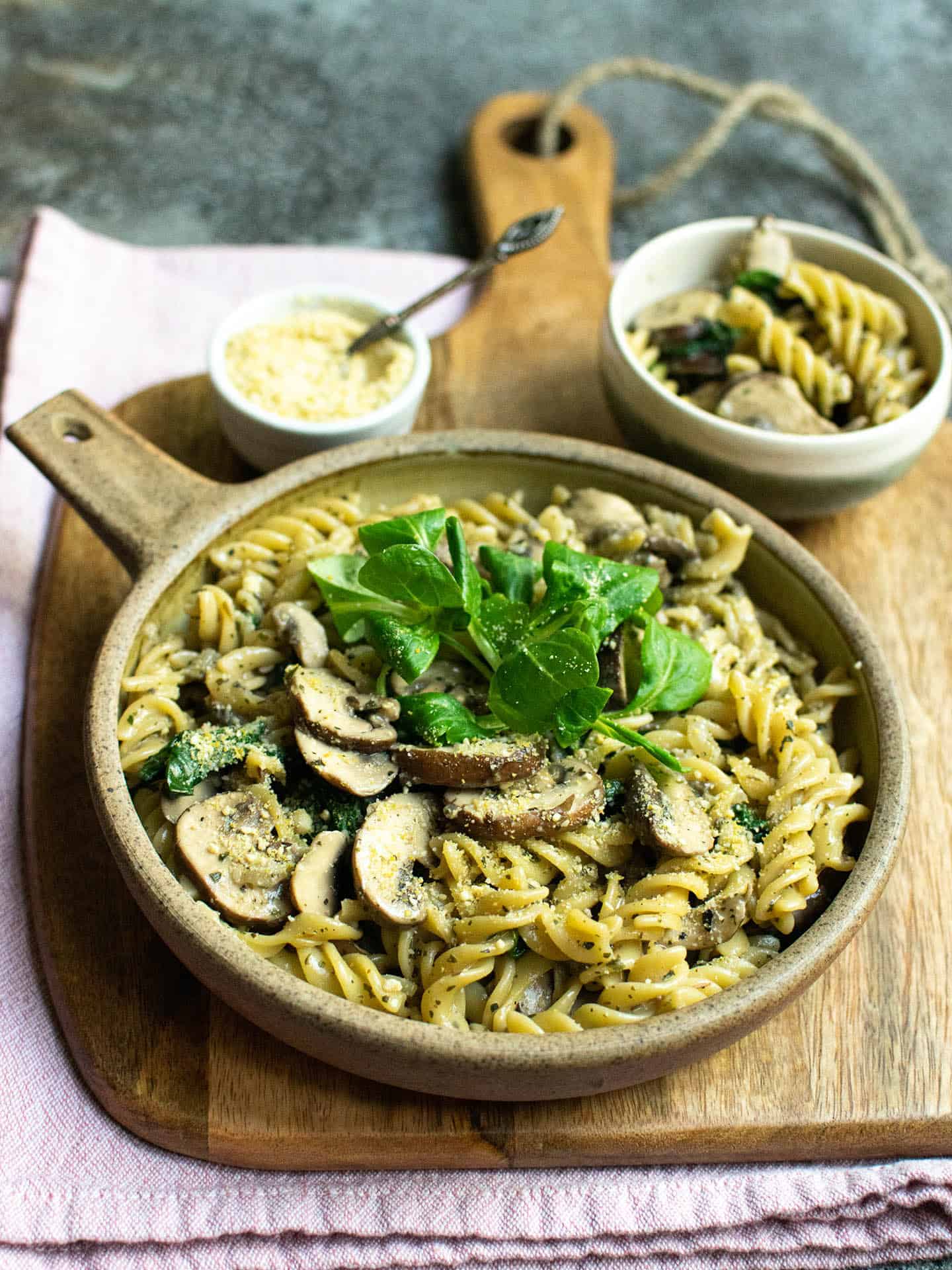 Creamy pasta served up in an earthy bowl, topped with mushrooms.
