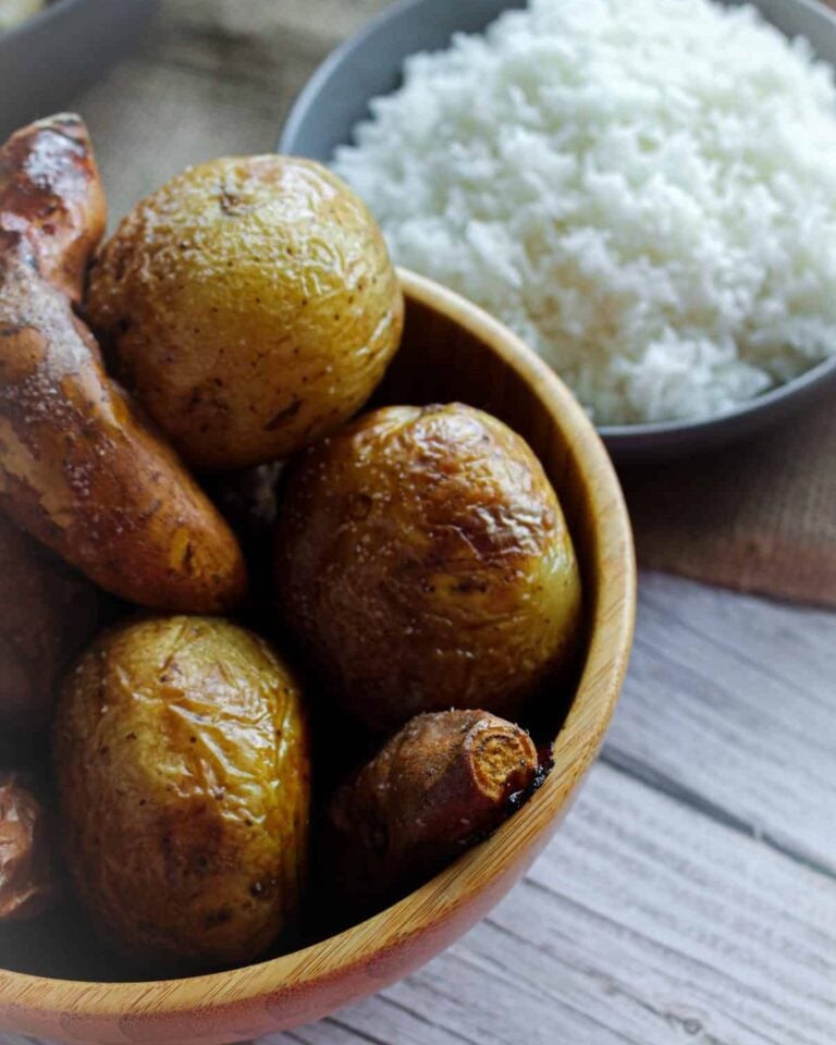 Jacket potatoes in a wooden bowl with a bowl of rice behind it.