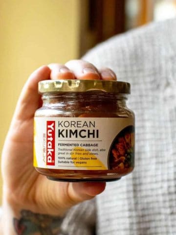 A man holding up a jar of kimchi