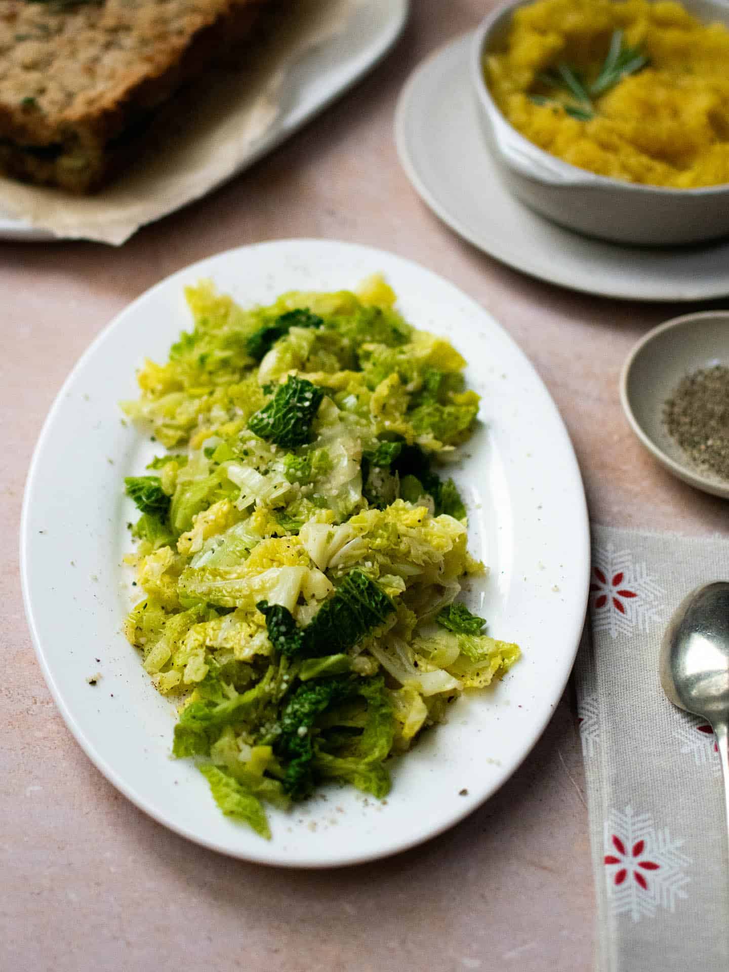 Leeks and cabbage on a plate with bits and bobs just visible around the edges – a dish with swede in it, a glimpse of a nut roast and cracked black pepper