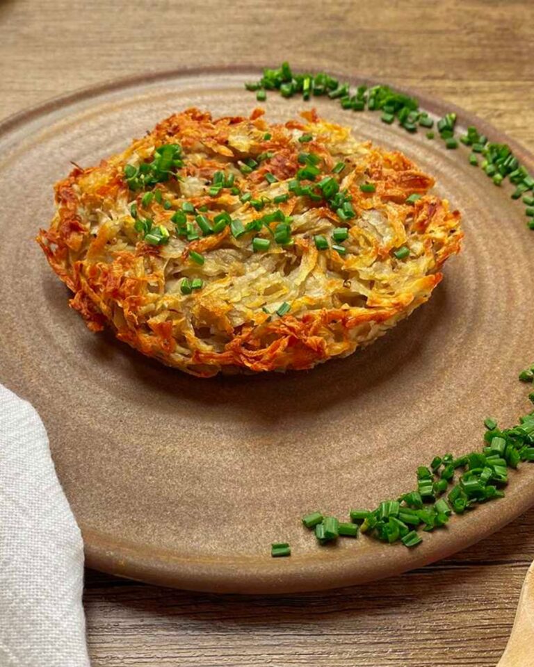 Potato rosti on a plate served with chopped fresh chives.