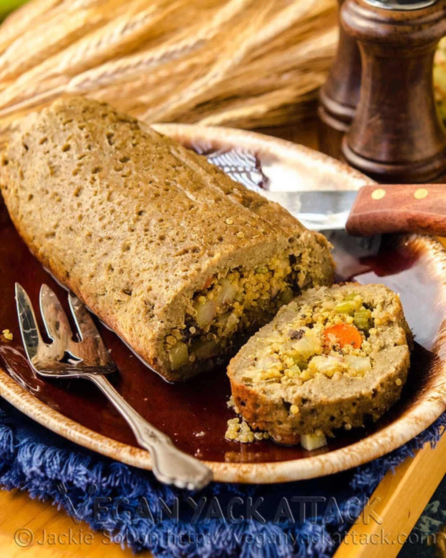 Stuffed seitan roast with serving knife and fork with one slice cut off