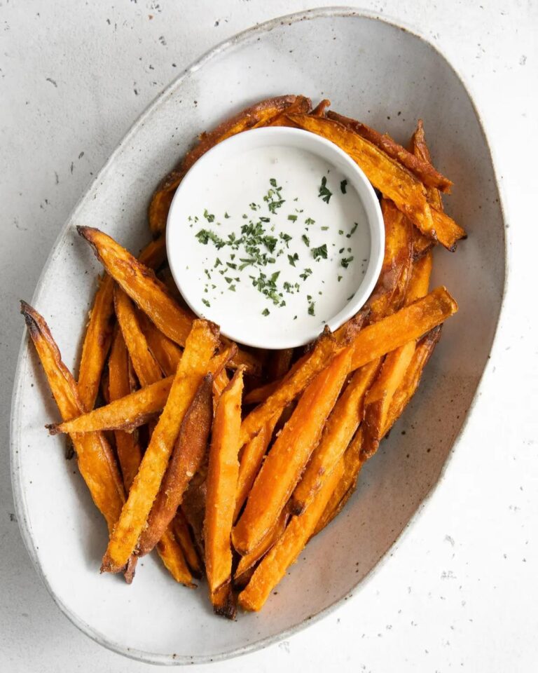Sweet potato fries on a serving plate with a dip.