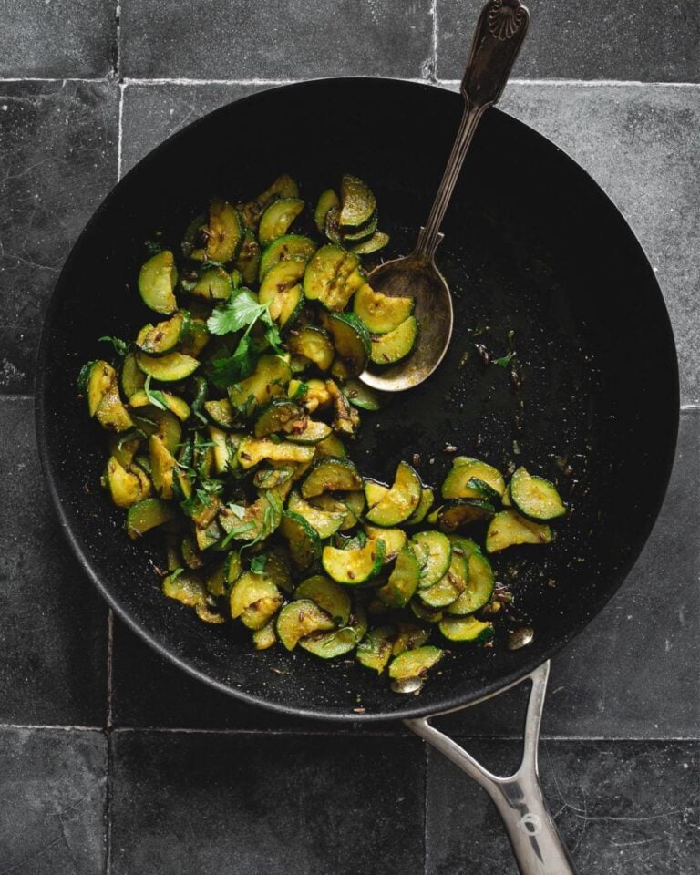 Courgette in a wok with a spoon.