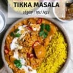A bowl of vegetable tikka masala with rice, topped with vegan yoghurt, coriander and chillies.