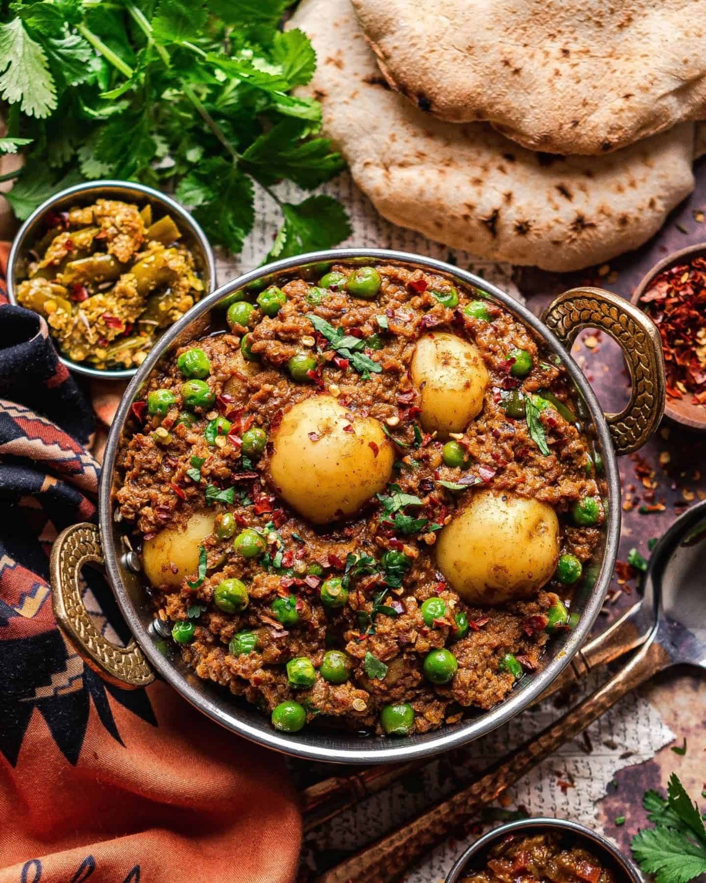 Vegan Keema in a balti dish showing potatoes and peas, with Indian bread and chutney in the background