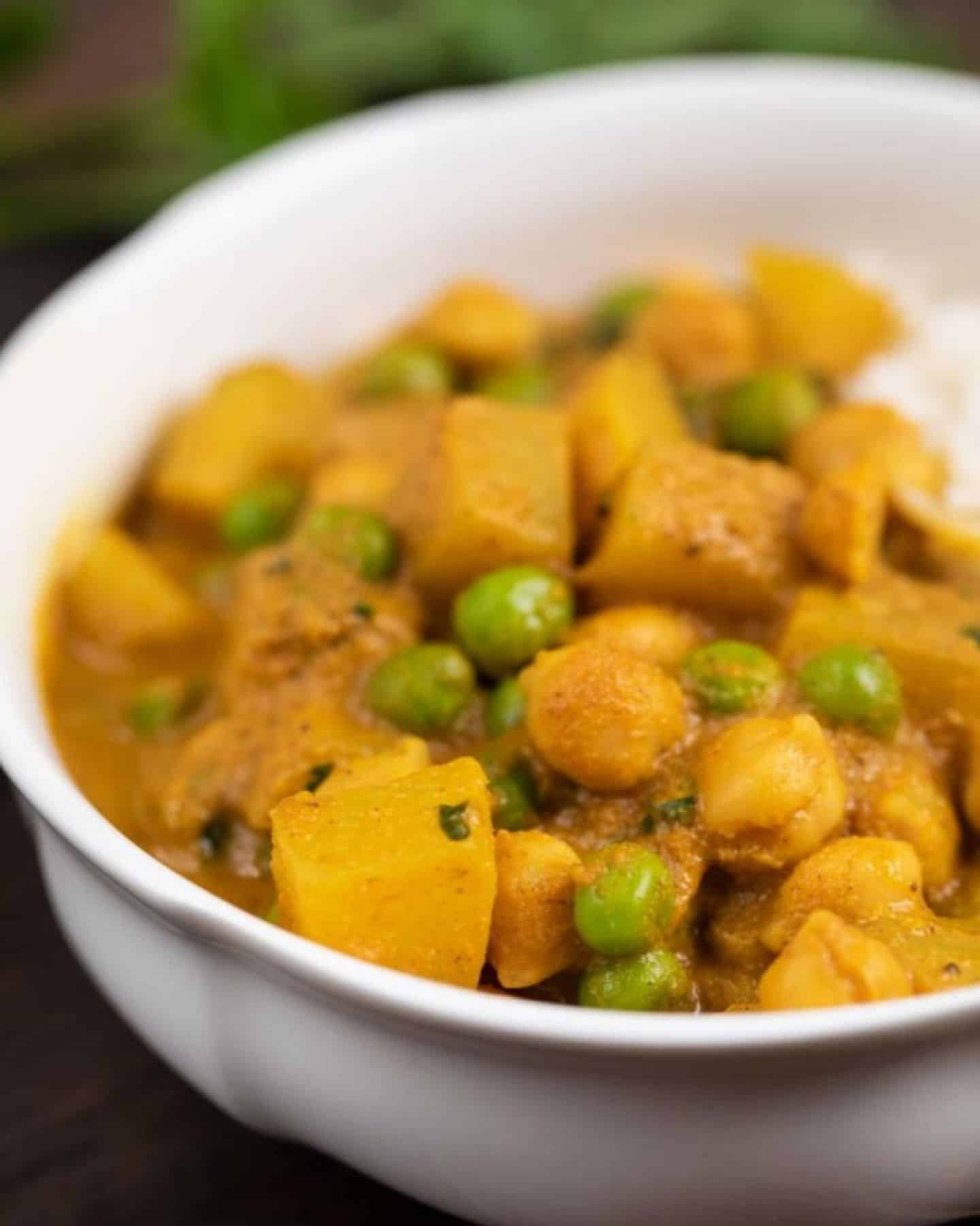 Close up of a potato and pea curry in a white bowl