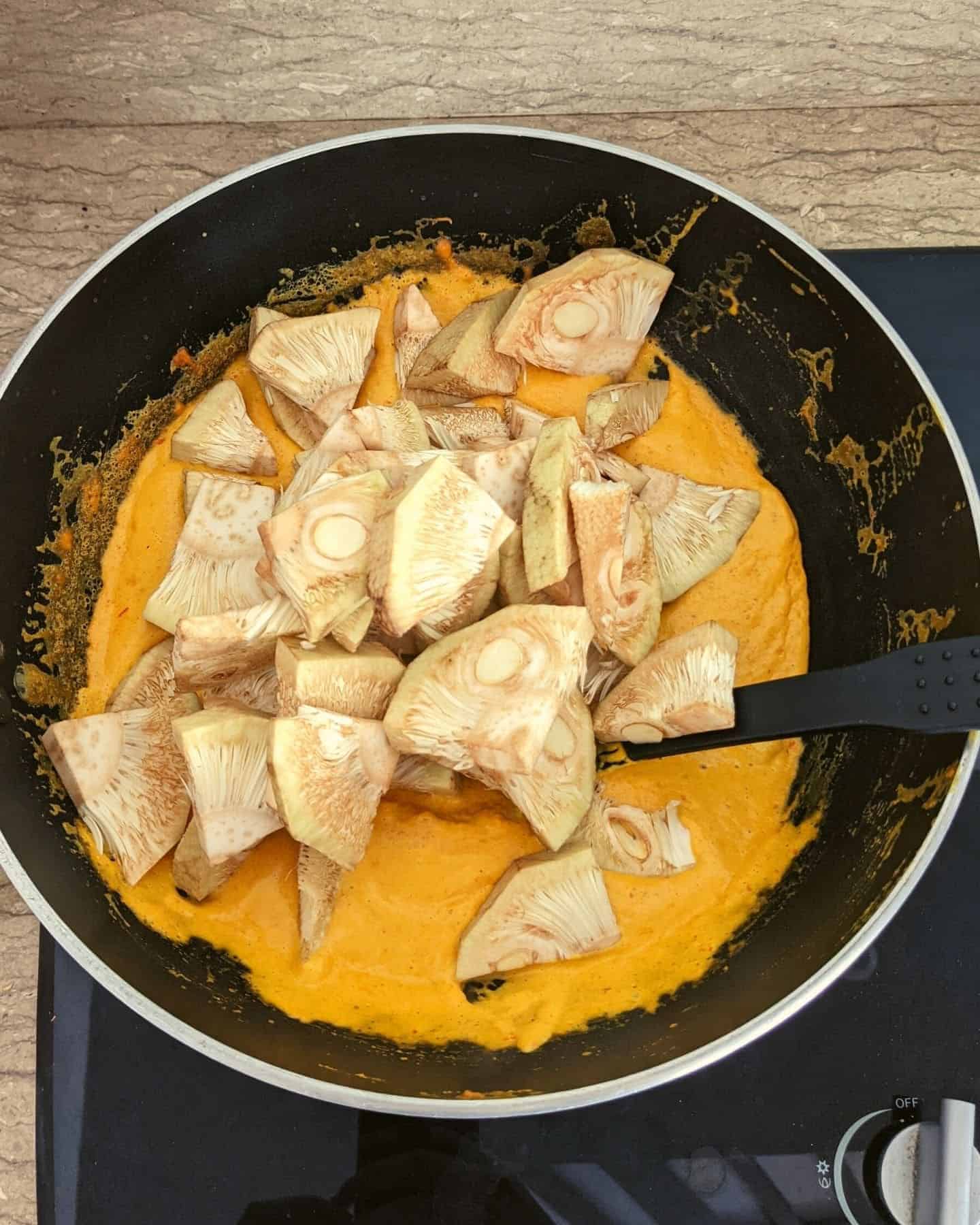 A pan with curry sauce in it, and chunks of jackfruit on top of it