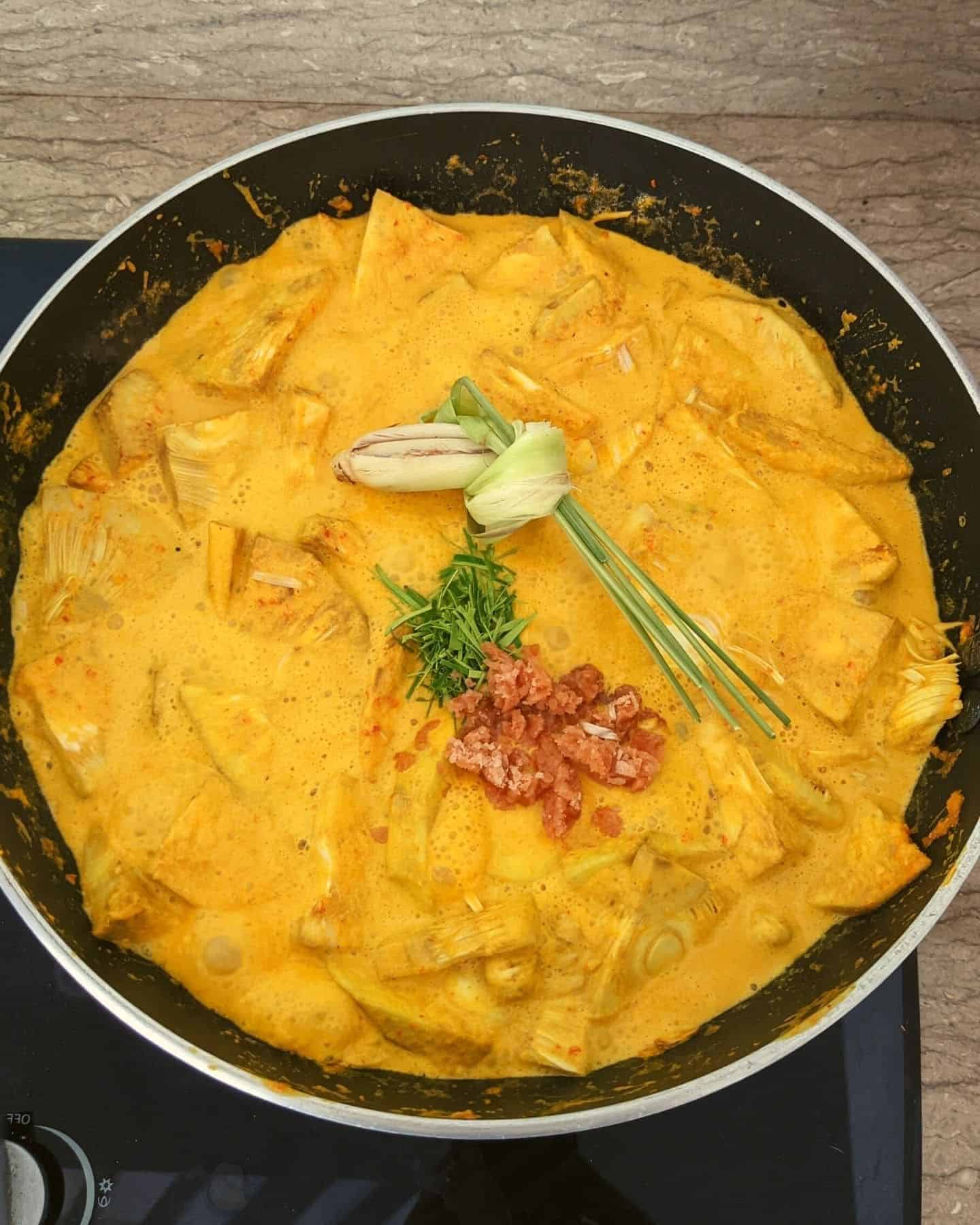 Lemongrass, sugar and kaffir lime leaf in a wok full with jackfruit rendang