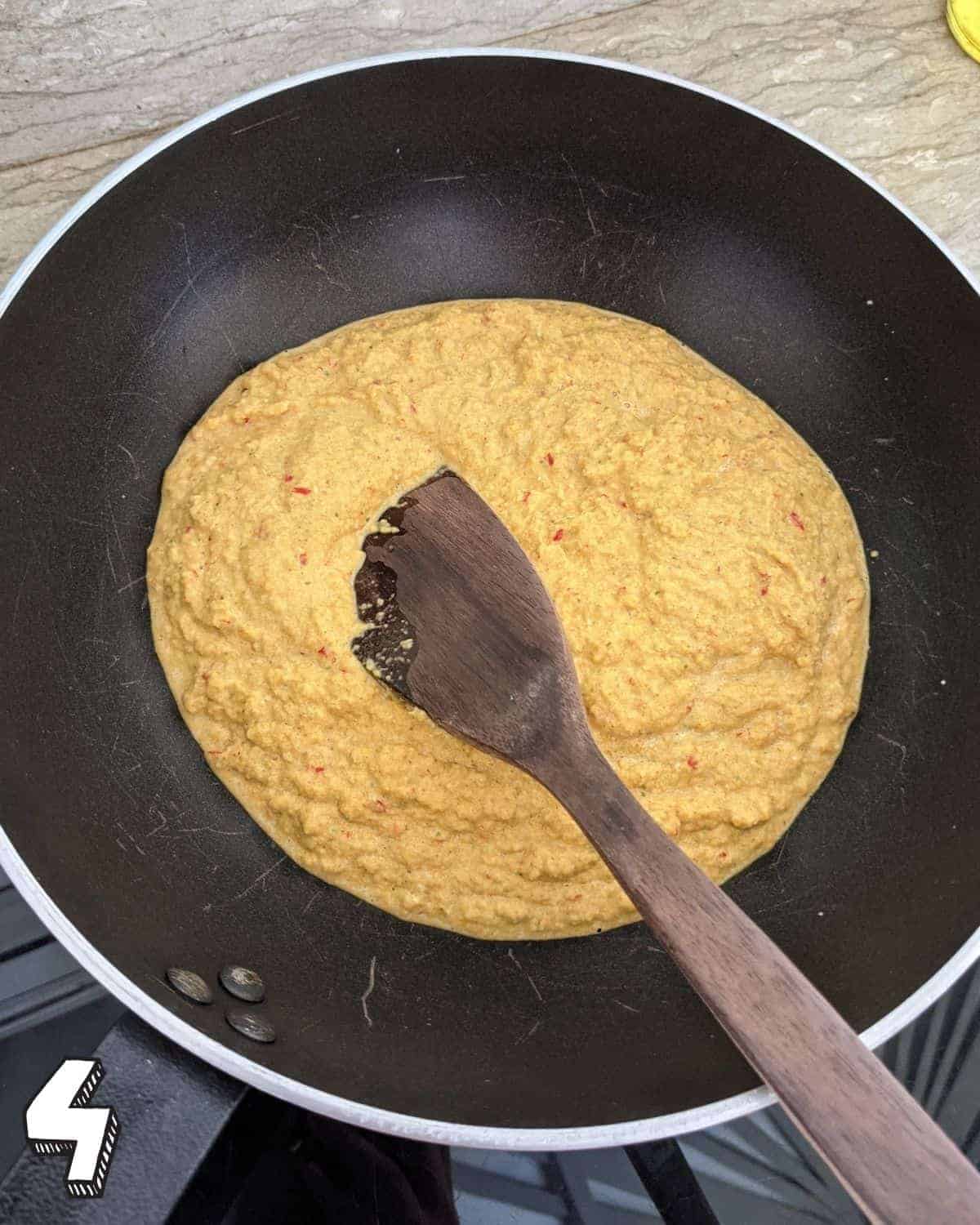 Yellow paste in a wok with a wooden spoon in it