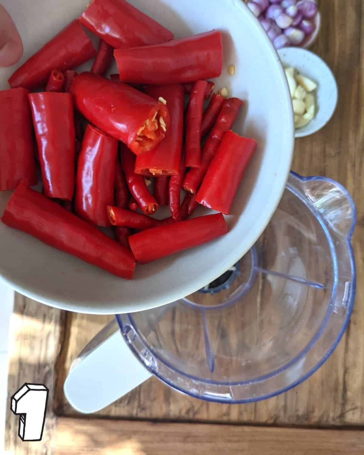 Chopped chillies being held over a blender jug
