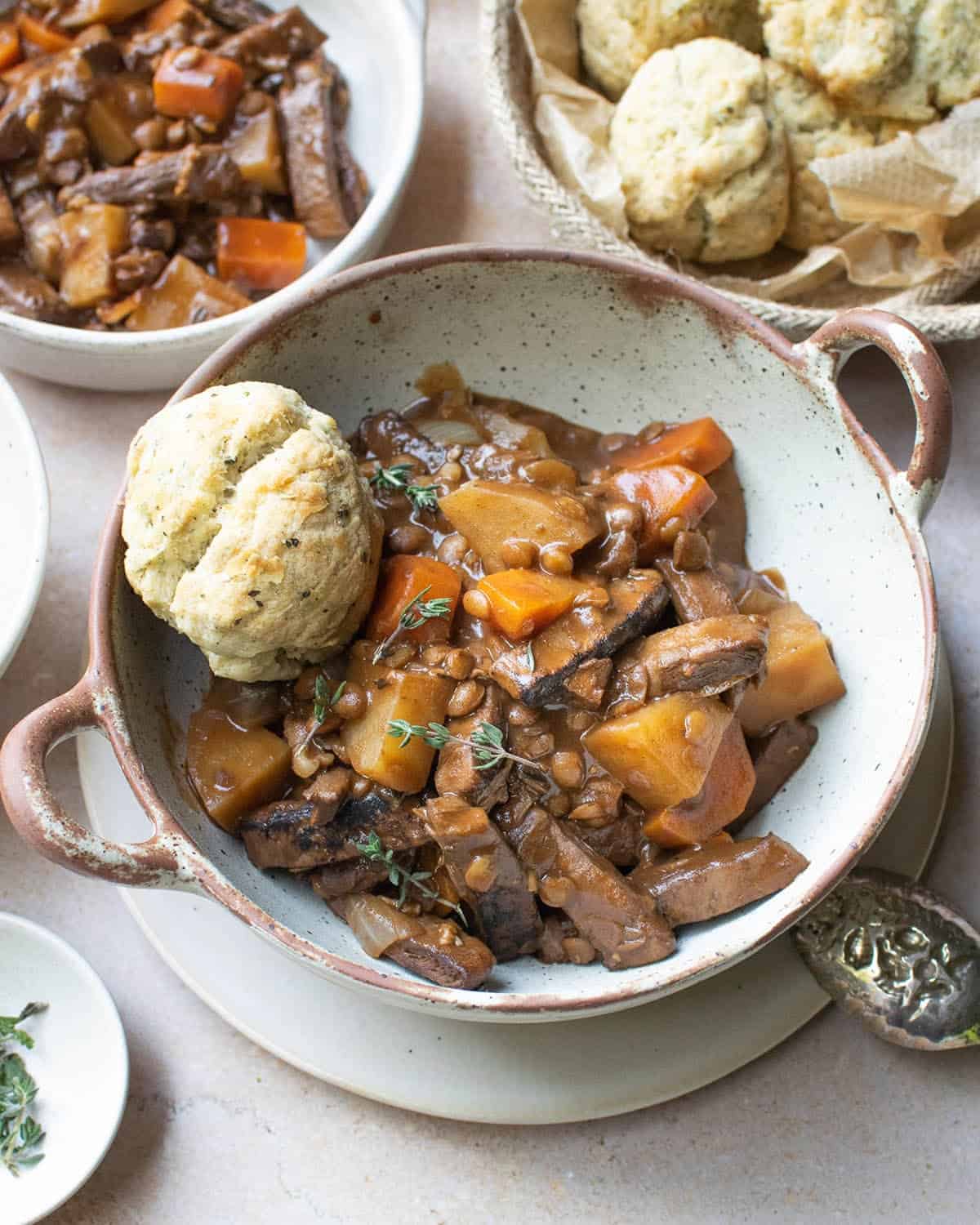 Vegan beef stew with vegetables and dumplings, with small dishes in the background