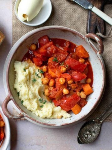 Vegan goulash in a bowl served with mashed potatoes and bread