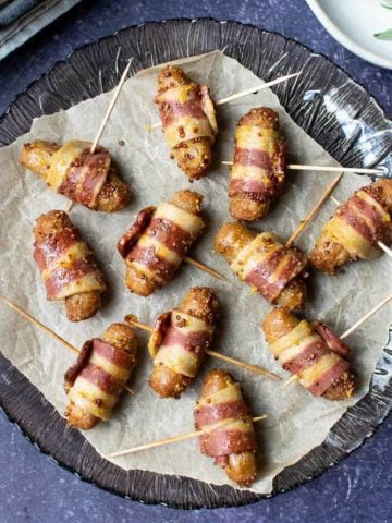 Vegan pigs in blankets on a round glass plate
