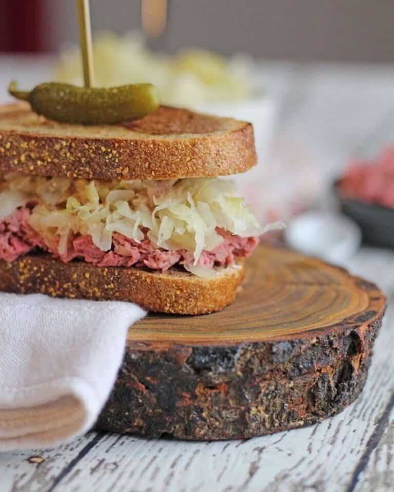 Vegan reuben sandwich with a pickle on a skewer through the bread.