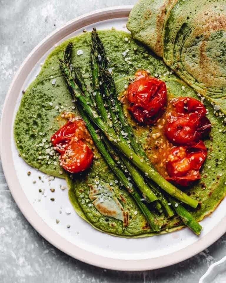 Green crepes topped with tomatoes and asparagus.