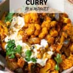 Cauliflower and eggplant curry in a bowl topped with yoghurt and fresh coriander.