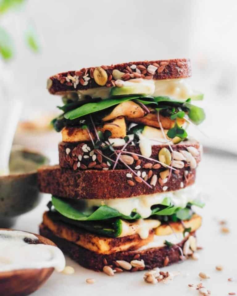Two halves of a grilled cheese sandwich with greens, stacked on each other.