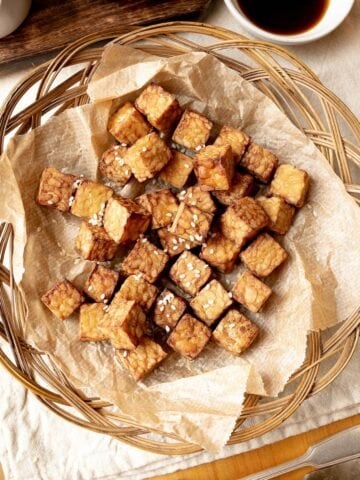 Chunks of air fried tempeh in a basket lined with parchment paper.