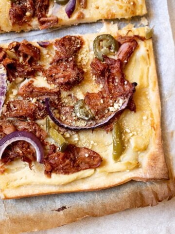 A square slice of vegan jackfruit pizza on a board.