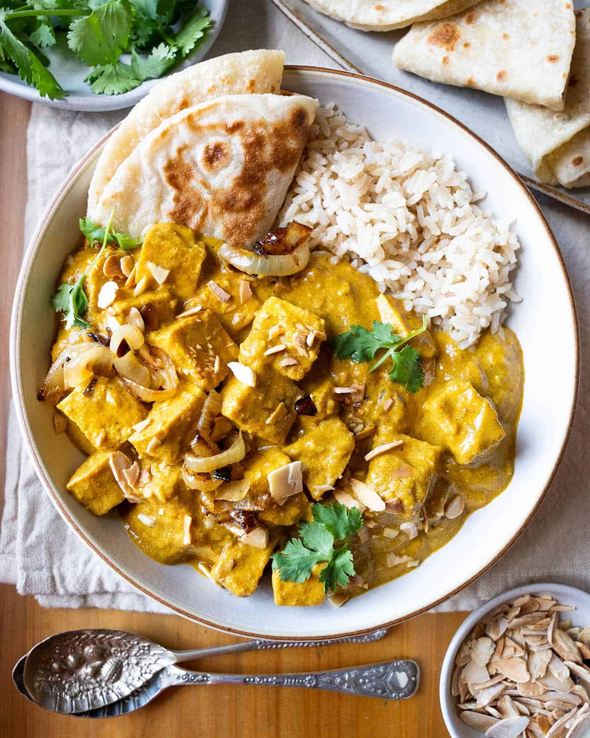Tofu korma in a bowl with rice and a roti on the side.