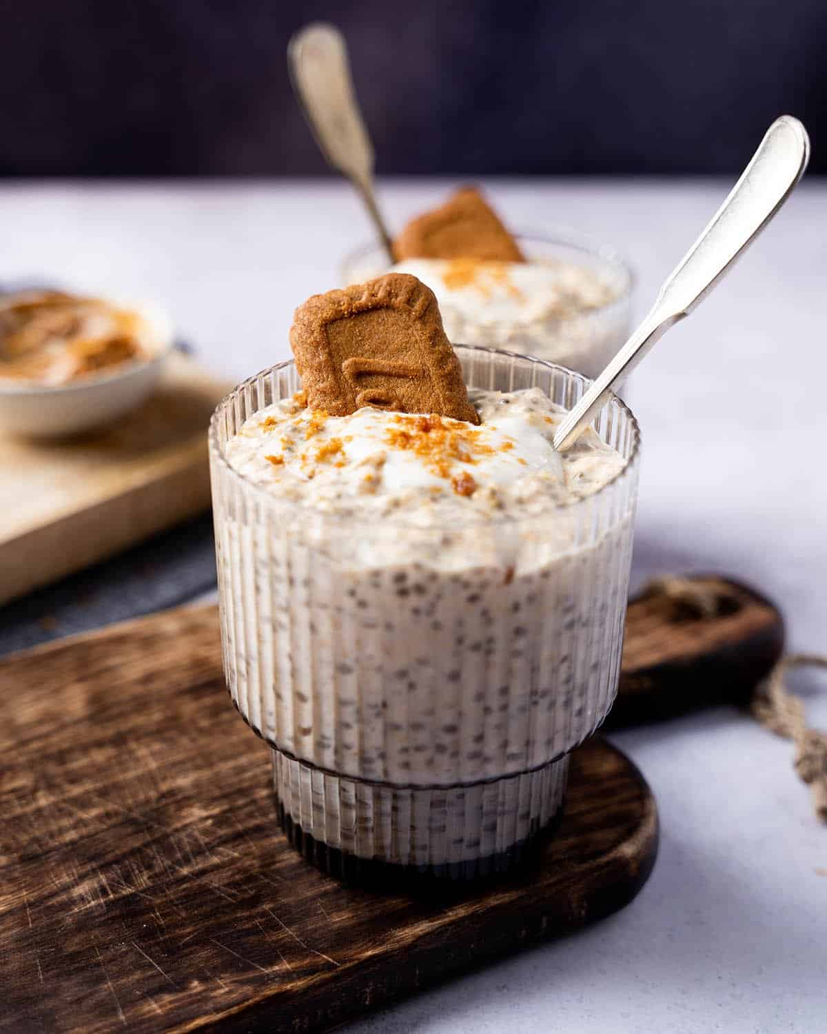 Biscoff overnight oats in a jar with a spoon in it, topped with a biscuit.