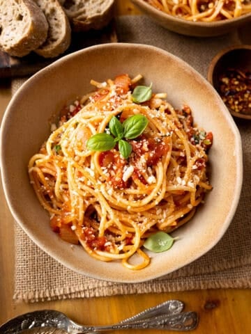 Parmesan topped spaghetti arrabiata with fresh basil and bread.