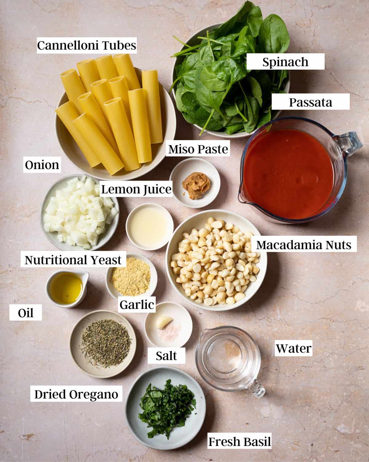 Vegan cannelloni ingredients in bowls on a marble surface.