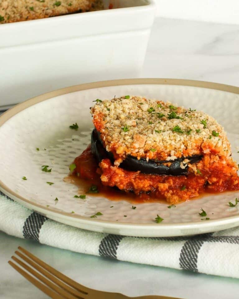 Vegan eggplant parmesan topped with fresh herbs on a plate.