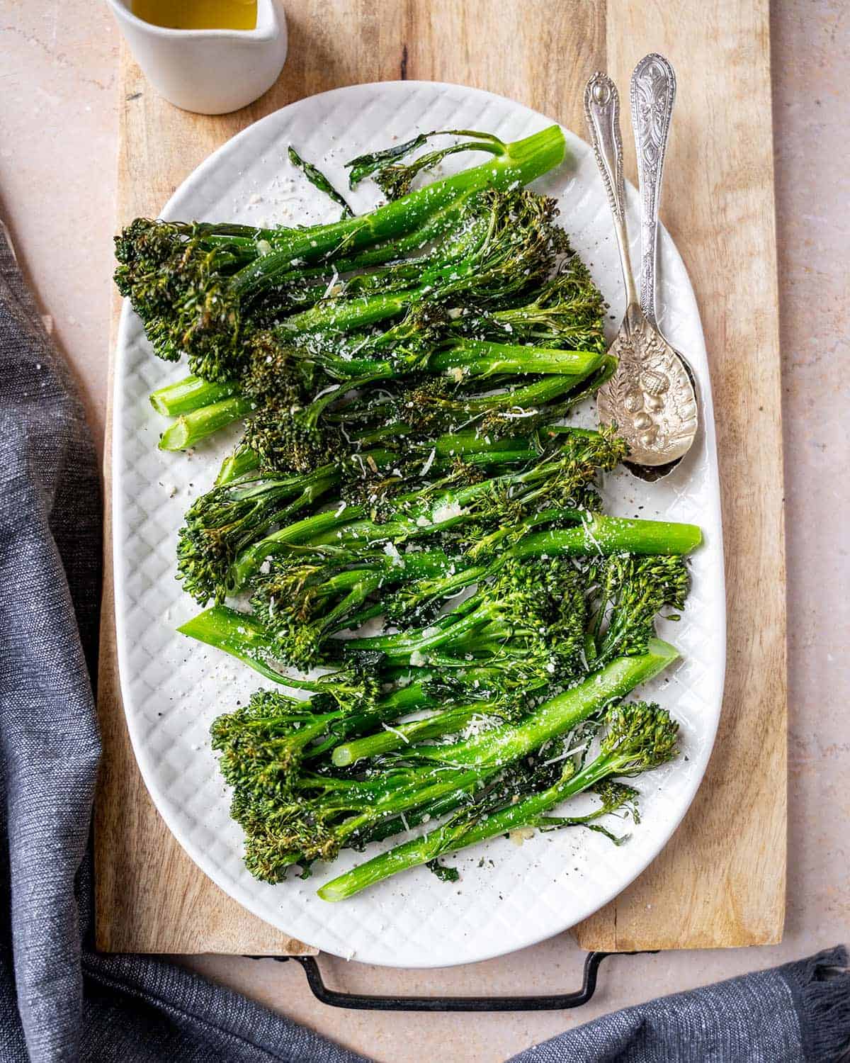 Broccolini on a serving plate seasoned with black pepper and topped with vegan parmesan.