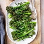 Baby broccoli on a serving platter with spoons.