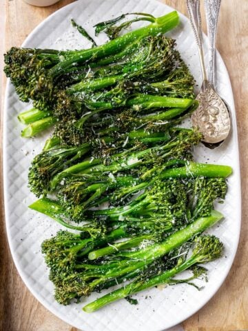 Baby broccoli on a serving platter with spoons.
