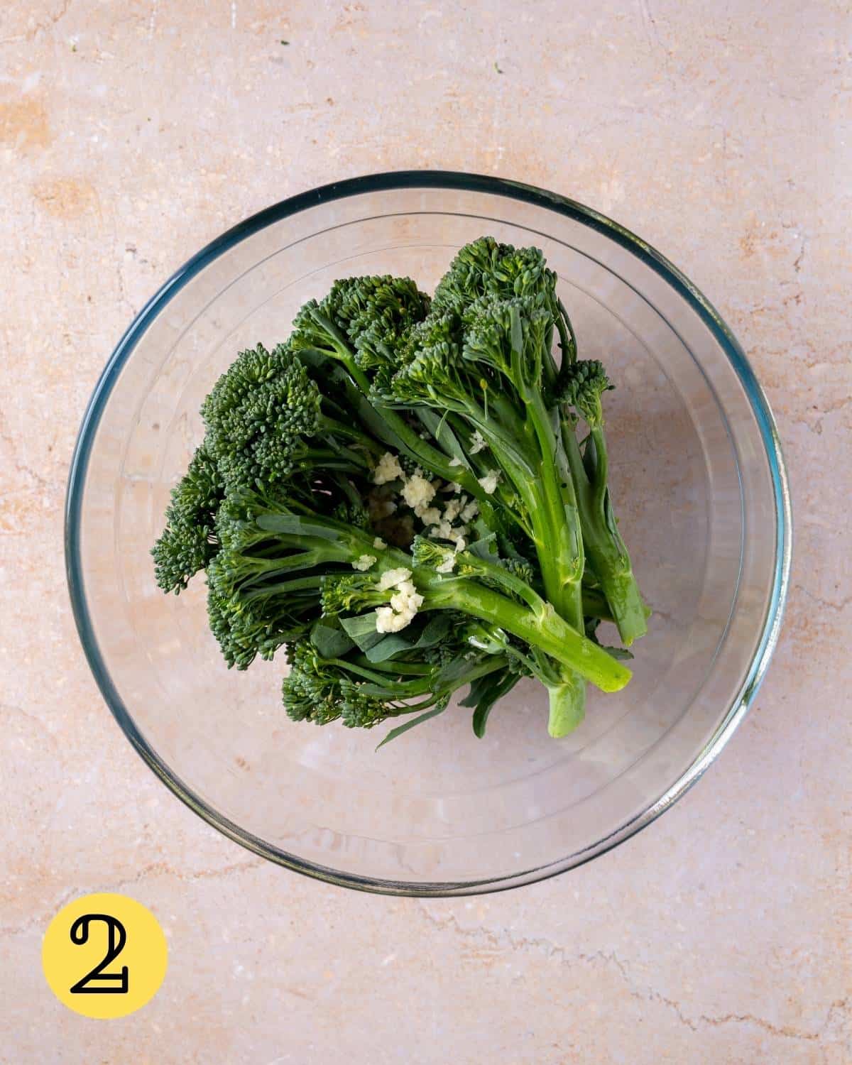 Broccoletti in a glass bowl with olive oil, garlic and salt.