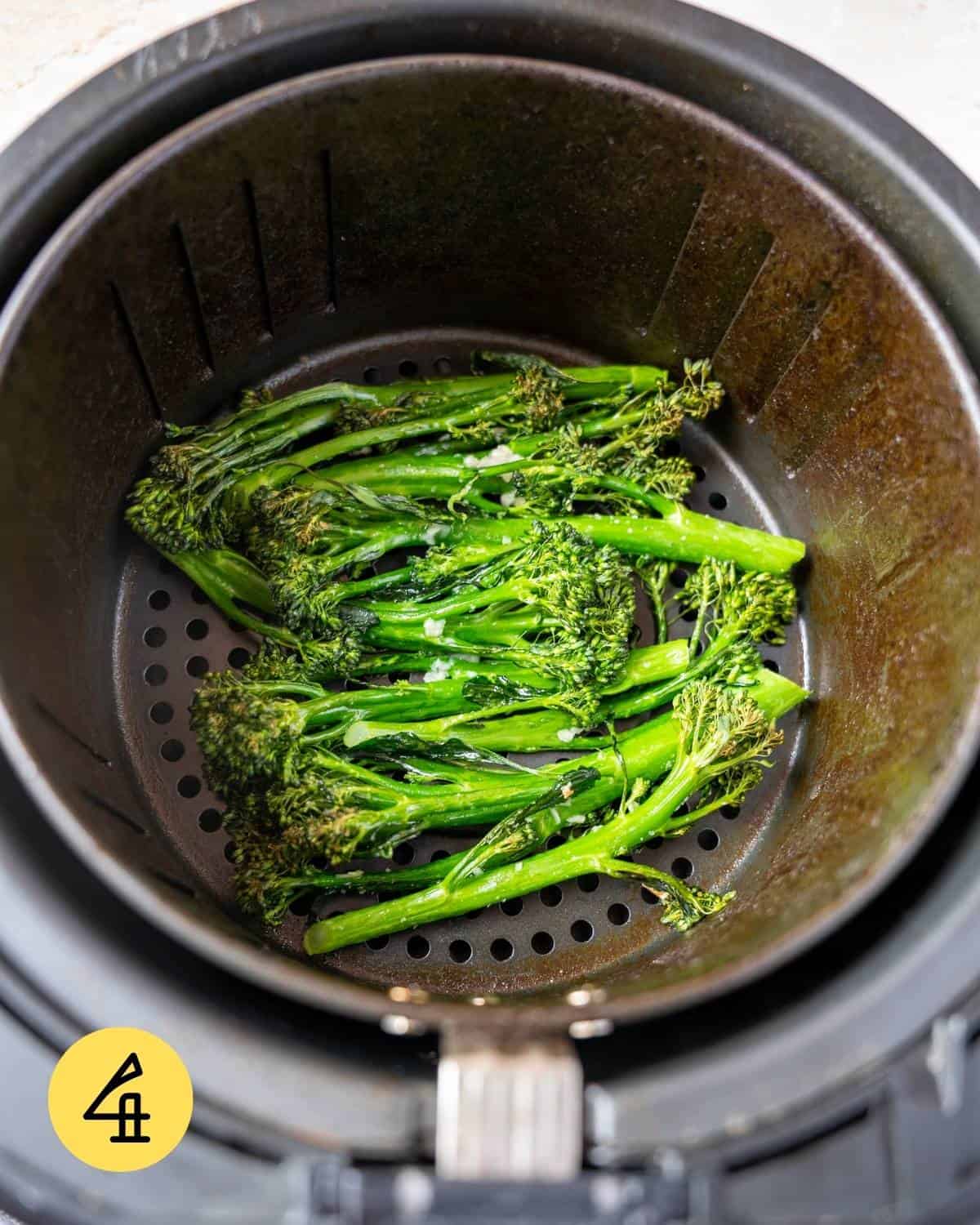 Cooked broccolini in an air fryer basket.