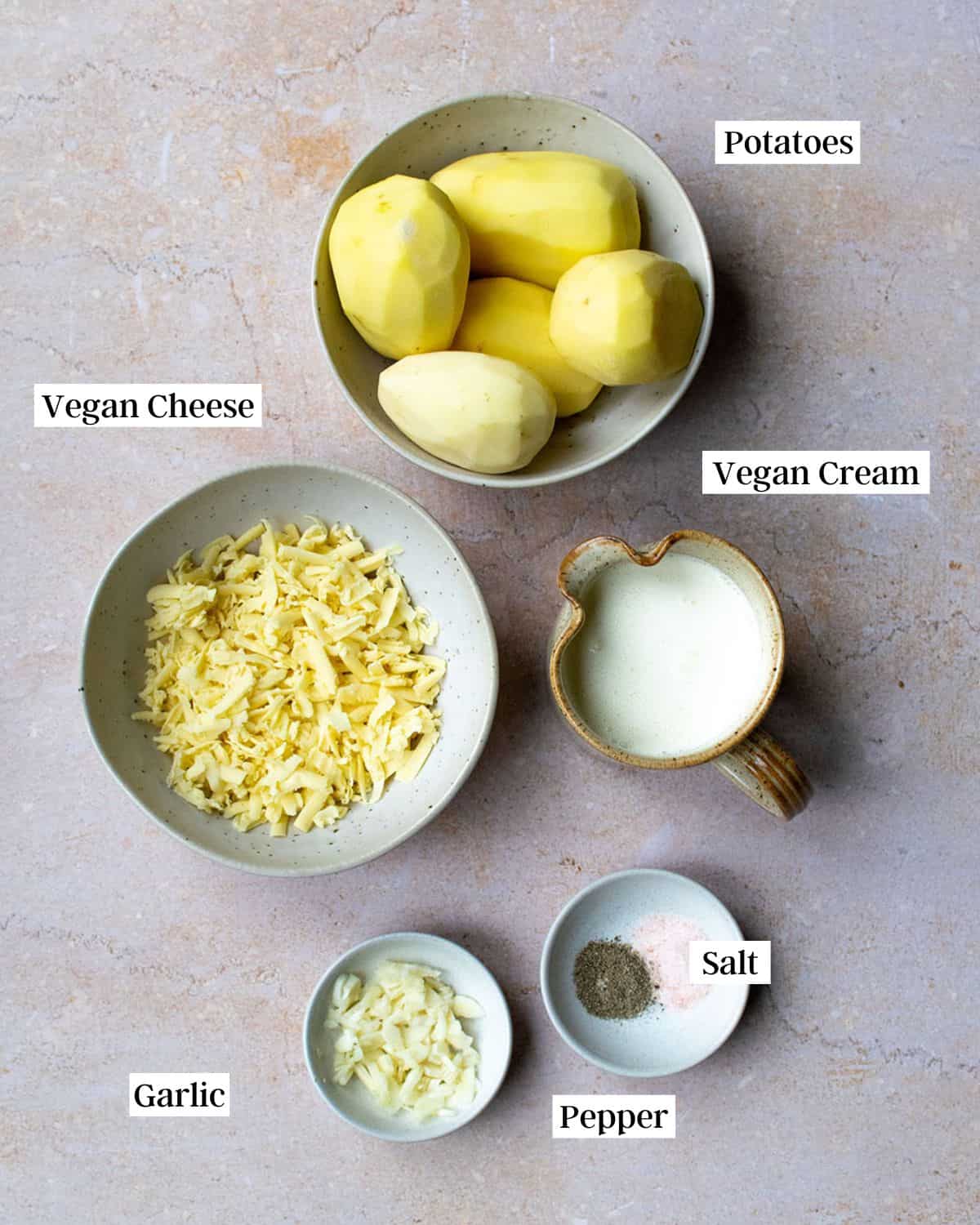 Ingredients for vegan dauphinoise potatoes on a marble surface.
