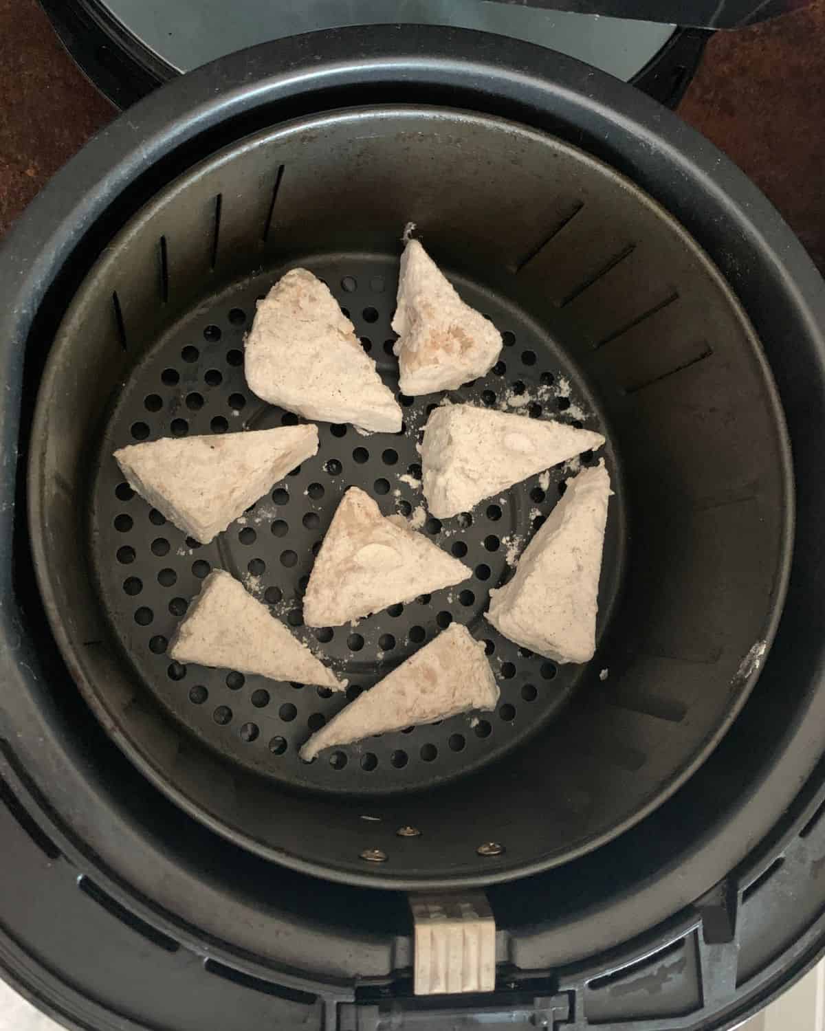 Coated young jackfruit pieces in an air fryer basket.