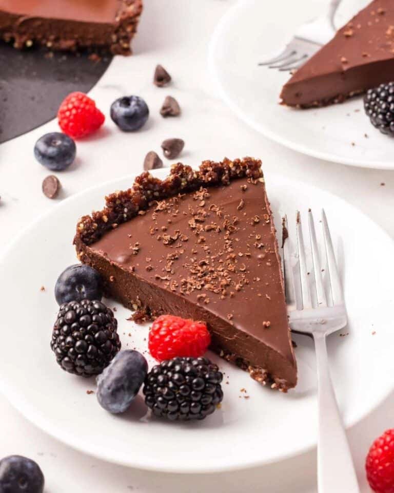 Chocolate ganache tart on a plate with berries.