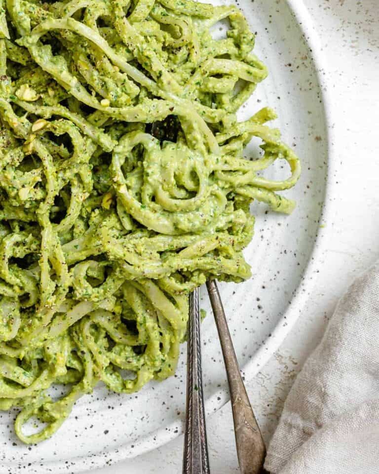 Avocado pesto with spaghetti on a plate with cutlery.