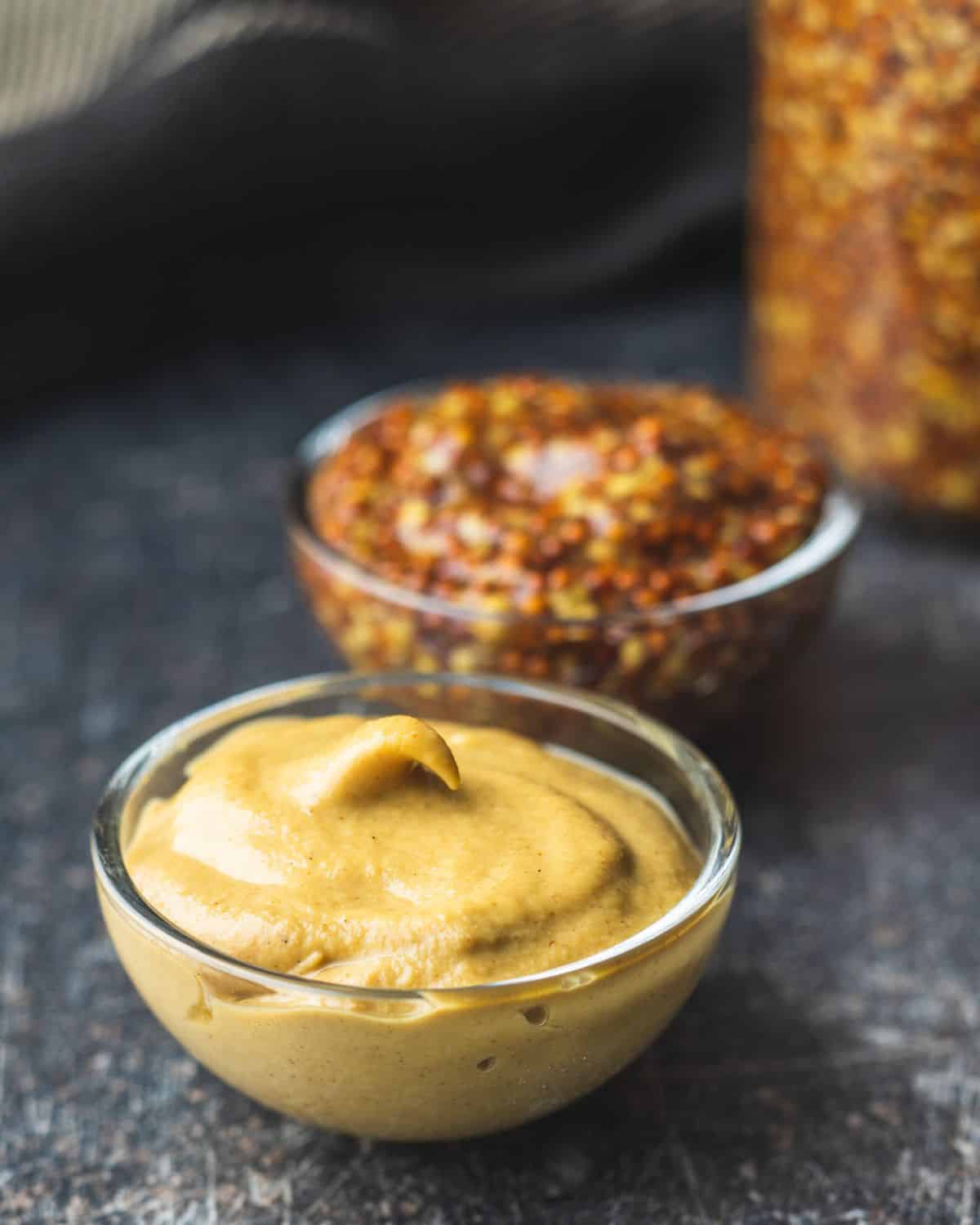 Dijon mustard and wholegrain mustard in glass bowls.