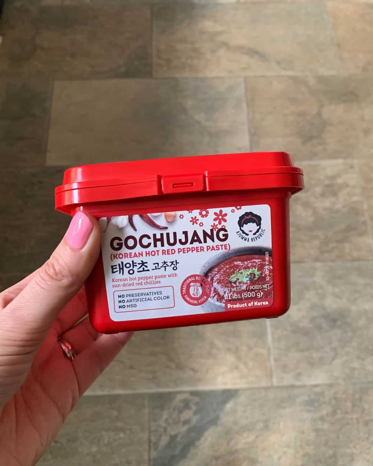 A pot of Gochujang paste held in a hand.