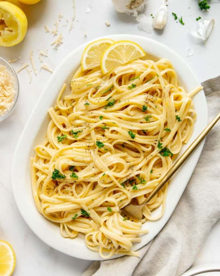 Lemon linguine pasta on a large plate with lemon slices.