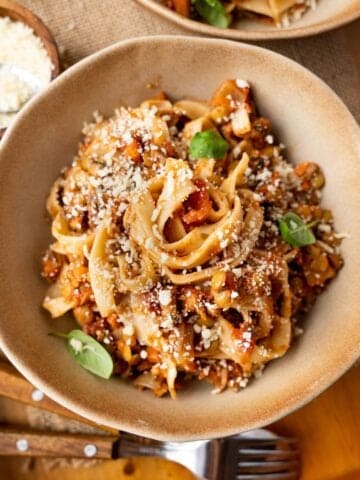 Lentil bolognese with tagliatelle and vegan parmesan cheese in a bowl.