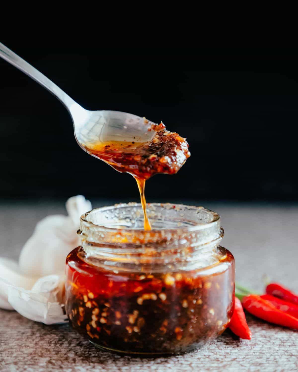 Chili sauce in a glass jar with a metal spoon.