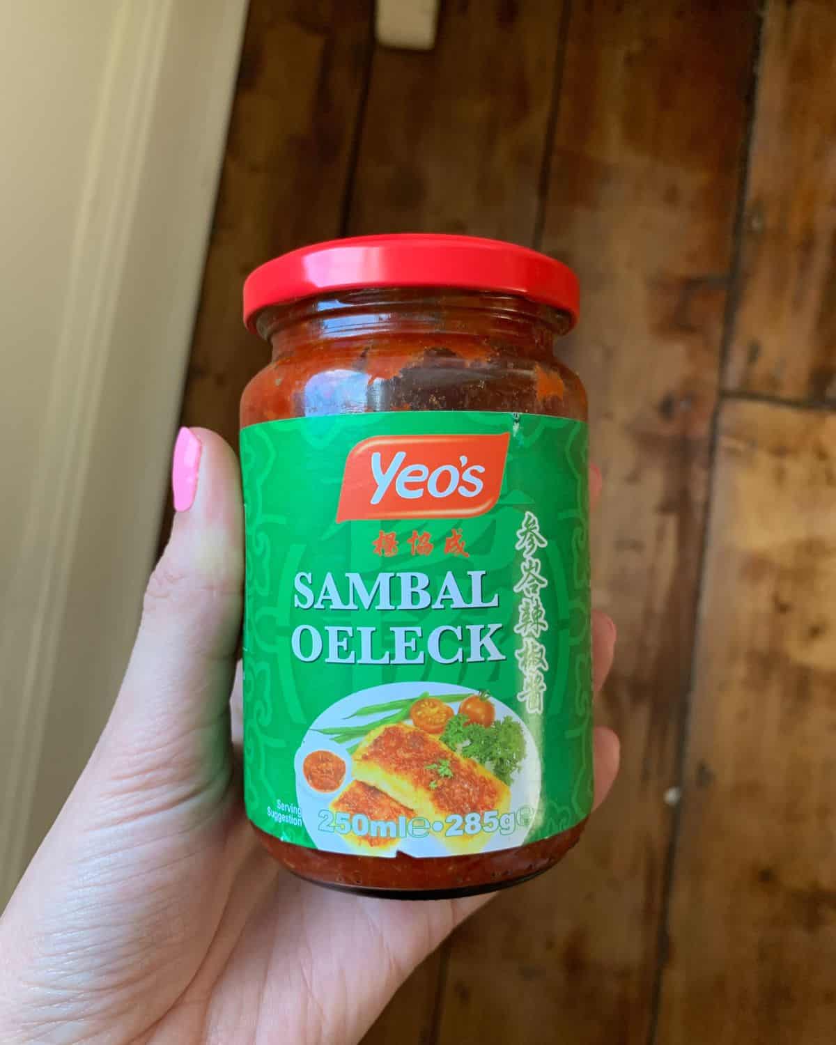 A jar of sambal olek held in a hand.